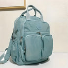 Light blue backpack with multiple zippered compartments, front pockets, and adjustable straps, ideal for travel and school. Durable and stylish design.