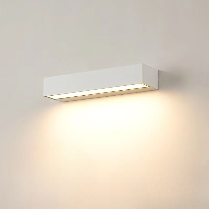 Modern white wall sconce with rectangular design, emitting warm LED light; ideal for contemporary home lighting and interior decor.