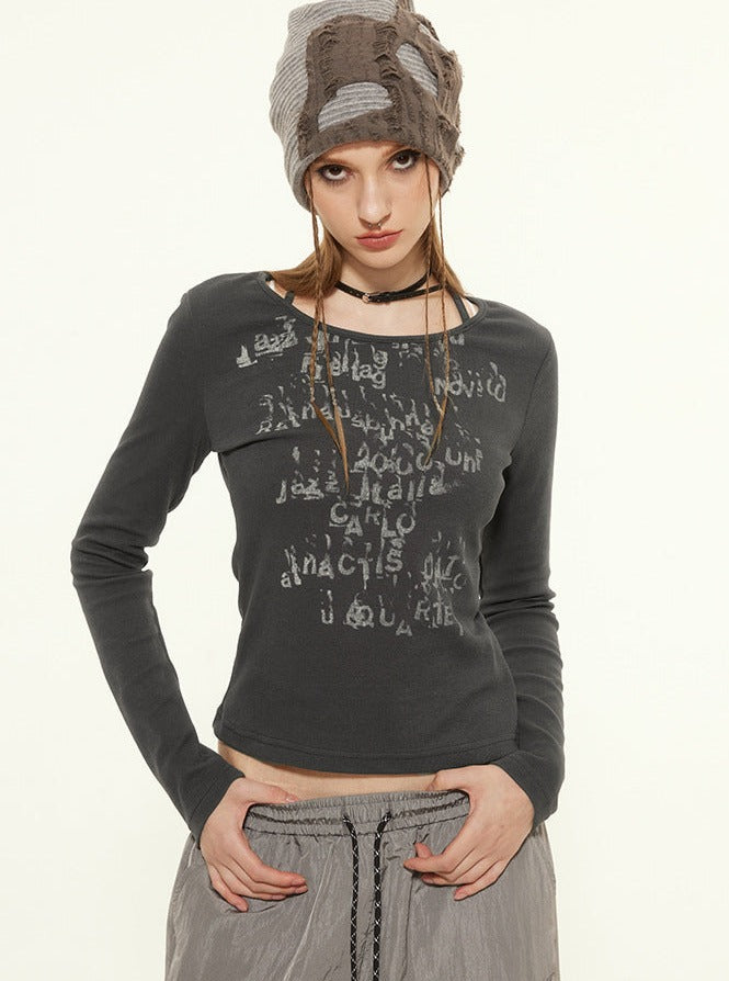 Young woman in a stylish gray graphic long-sleeve top and beanie, posing confidently. Fashionable casual wear, trendy street style outfit.