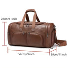 Brown leather duffel bag with adjustable shoulder strap, multiple zippered pockets, and dimensions 57cm x 28cm x 28cm. Ideal for travel and gym use.