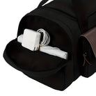 Black travel duffel bag with open side pocket showing a white laptop charger and cable. Ideal for tech-savvy travelers. Durable and spacious design.