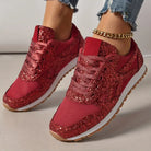 Red glitter sneakers with white soles and gum outsoles, worn with frayed jeans and a gold anklet. Fashionable women's footwear, casual style.