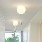 Modern ceiling lights with round white fixtures and hanging penguin designs in a bright hallway, featuring minimalist home decor and natural light.