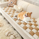 Corgi dog lounging on a beige and white checkered sofa cover, cozy living room setting with plush decor, fluffy rug, and slippers.