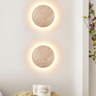 Modern round wall sconces with warm LED lighting on a white wall, minimalist home decor, contemporary lighting fixtures, interior design accents.