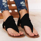 Black open-toe sandals with unique wrap design, worn with blue jeans. Stylish summer footwear for women, casual and comfortable.