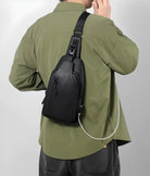 Man wearing a stylish black crossbody sling bag with USB charging port, paired with a green shirt. Ideal for travel, tech-savvy urban lifestyle.