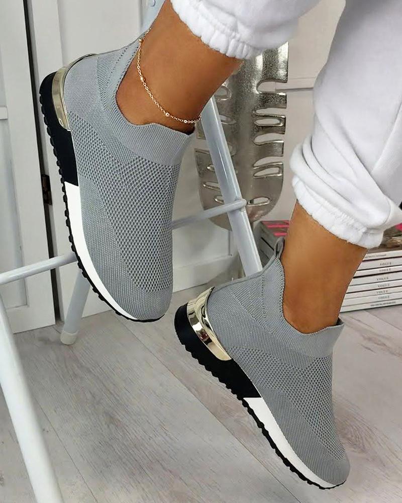 Gray slip-on sneakers with metallic accents, worn with white joggers. Stylish, comfortable footwear for casual wear. Perfect for fashion-forward looks.