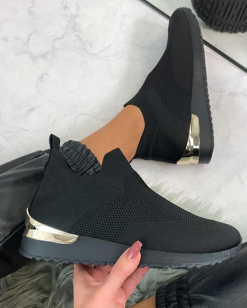 Black knit slip-on sneakers with gold heel detail, worn with black pants on a marble floor. Stylish, comfortable footwear for casual fashion.