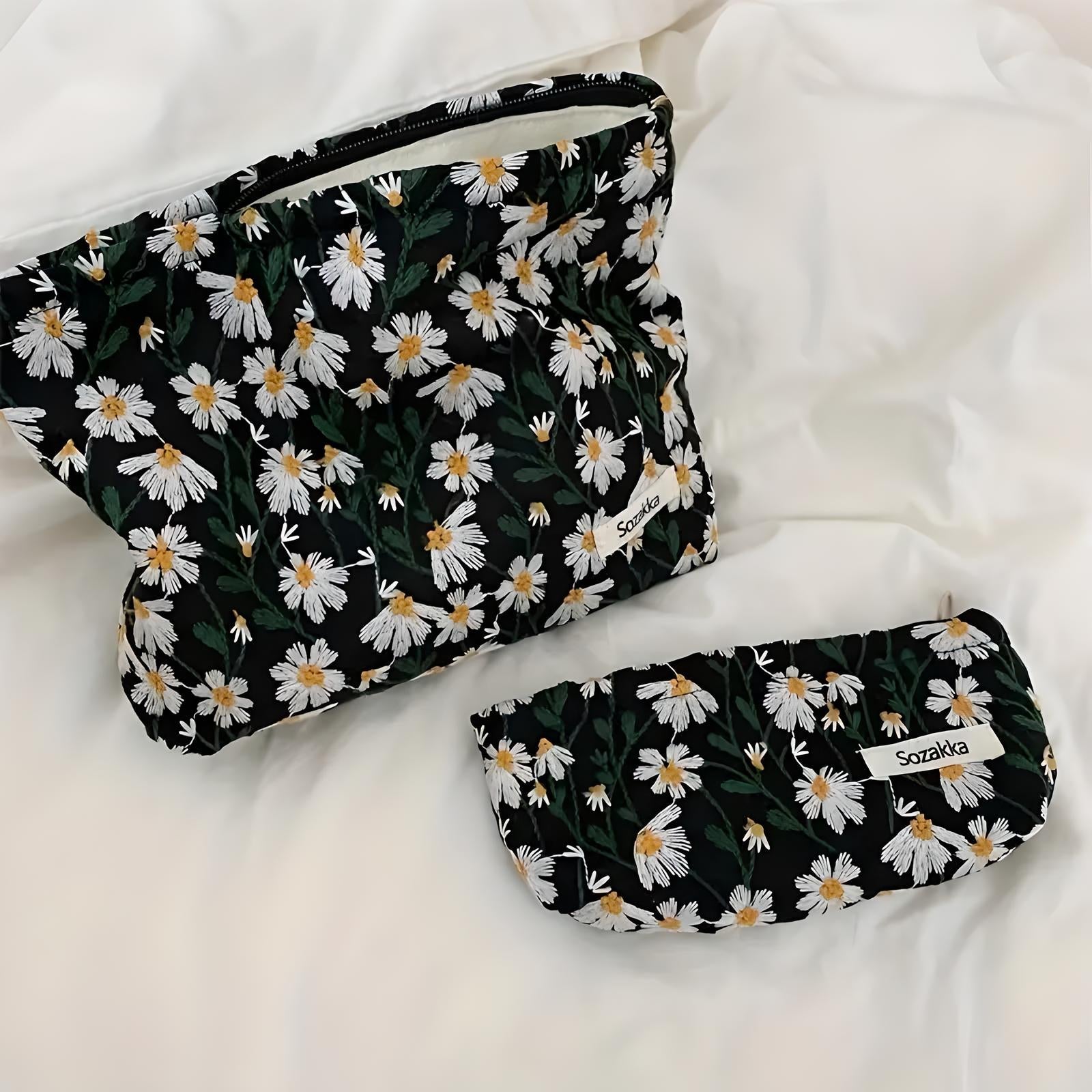 Floral cosmetic bags with daisy pattern on white fabric background, featuring two sizes, perfect for travel and makeup storage.