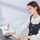 Woman using laptop with pink portable humidifier on desk; modern home office setup, stylish work environment, productivity essentials.