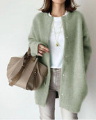 Woman in stylish green cardigan, white shirt, and beige handbag. Fashionable casual outfit, trendy accessories, modern women's fashion.