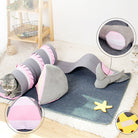 Cat tunnel toy with pink and gray shark design on a soft mat, featuring interactive elements for playful cats. Perfect for indoor pet entertainment.