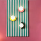 Modern wall art with three geometric lights on a striped teal and white background, set against a pink wall. Contemporary home decor lighting.