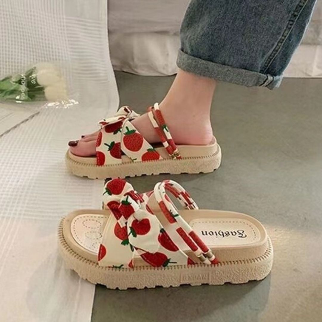 Strawberry print sandals with thick beige soles, worn with rolled-up jeans. Trendy summer footwear, casual style, women's fashion.