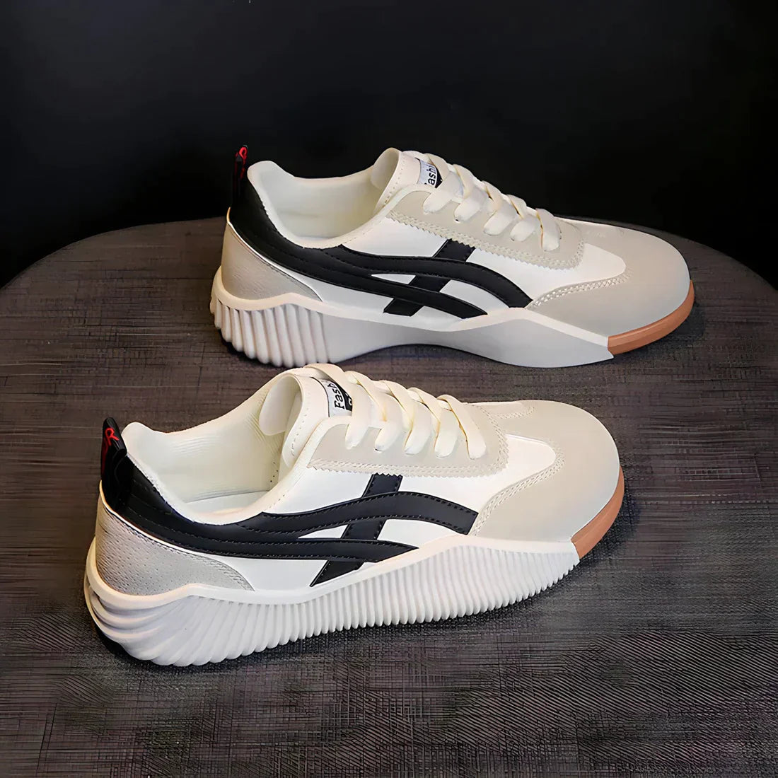 White and black athletic sneakers with a sleek design, featuring a textured sole and stylish side stripes, perfect for casual wear and sports activities.