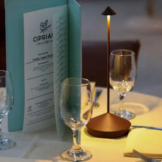 Elegant restaurant table setting with a menu, modern table lamp, and wine glasses at Cipriani. Perfect ambiance for fine dining and romantic dinners.