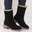 Black suede winter boots with faux fur lining, chunky wooden heel, and rugged sole, paired with dark jeans. Stylish women's footwear for cold weather.