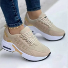 Beige women's sneakers with white soles and gold accents, featuring a mesh design and thick platform, worn with blue jeans. Fashionable casual footwear.