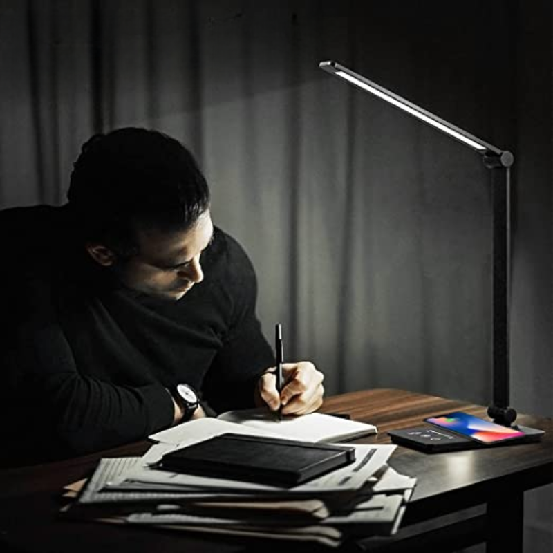 Man writing under modern LED desk lamp with adjustable arm, sleek design, and energy-efficient lighting, ideal for office or study environments.