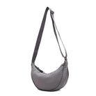 Gray crescent-shaped crossbody bag with adjustable strap, minimalist design, lightweight nylon material, ideal for travel and everyday use.