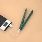 Portable green hair straightener connected to a power bank on a beige background. Wireless styling tool, travel-friendly, USB charging.