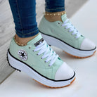 Mint green platform sneakers with white laces and rubber soles, worn with blue jeans and gold anklets. Fashionable casual footwear for women.