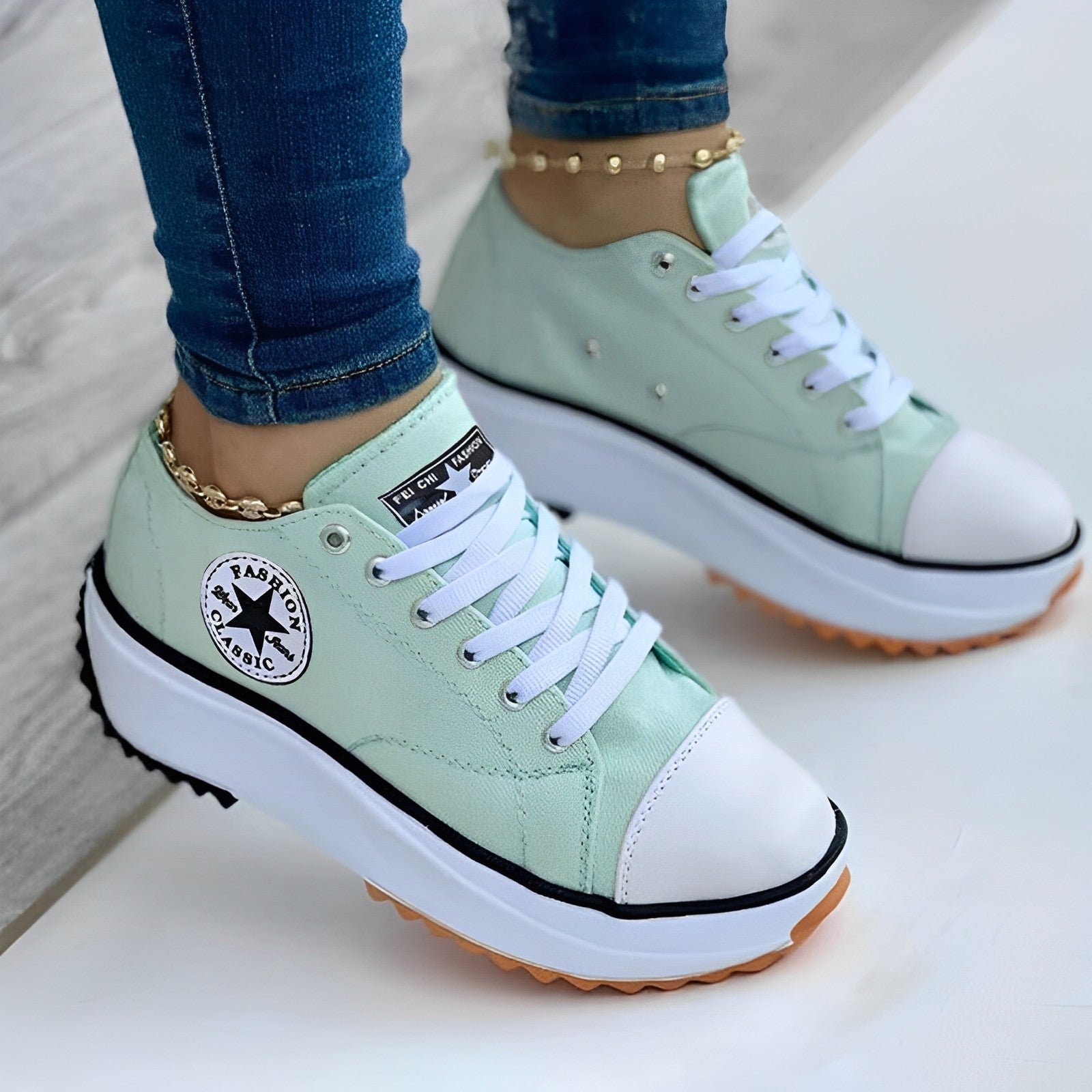 Mint green platform sneakers with white laces and rubber soles, worn with blue jeans and gold anklets. Fashionable casual footwear for women.