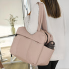 Woman carrying a stylish beige tote bag with a water bottle pocket, perfect for work or travel. Modern fashion accessory, versatile and functional design.