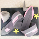 Plush shark tail blanket on a soft gray mat with yellow starfish toys, featuring pink and gray colors, perfect for cozy home decor and kids' play.