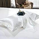 Luxurious white silk pillowcase on a bed with a green coffee cup and saucer, perfect for enhancing bedroom decor and promoting restful sleep.