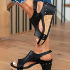 Black wedge sandals with cork platform and studded accents, worn with distressed jeans. Stylish women's footwear for casual summer fashion.