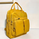 Yellow backpack with multiple zippered compartments, durable fabric, and top handles, ideal for travel and school. Stylish and functional design.