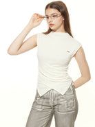 Woman in stylish white sleeveless top and metallic silver pants, adjusting glasses. Fashionable casual outfit, modern women's clothing.