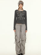 Woman in gray graphic long-sleeve top, baggy cargo pants, and knit beanie. Fashionable streetwear outfit, casual urban style.