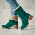 Green suede ankle boots with chunky heels and faux fur trim, paired with blue jeans. Stylish winter footwear, perfect for casual and trendy outfits.