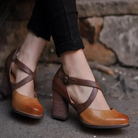 Brown leather high heel shoes with cross straps, worn with black pants, stylish footwear for women, perfect for casual or formal occasions.