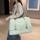 Woman carrying a stylish mint green quilted duffel bag with shoulder strap, perfect for travel or gym use. Fashionable and functional accessory.