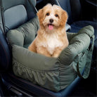 Small dog sitting in a green pet car seat booster on a car seat, ensuring safety and comfort during travel. Pet travel accessory, dog car seat.