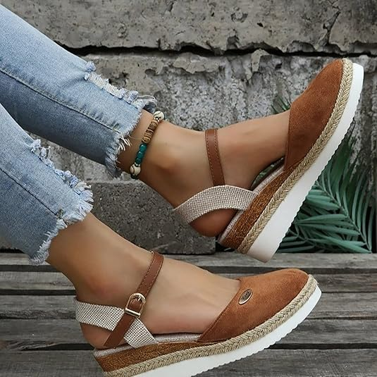 Women's brown espadrille sandals with ankle strap, worn with distressed jeans. Stylish summer footwear, casual fashion, comfortable platform sole.