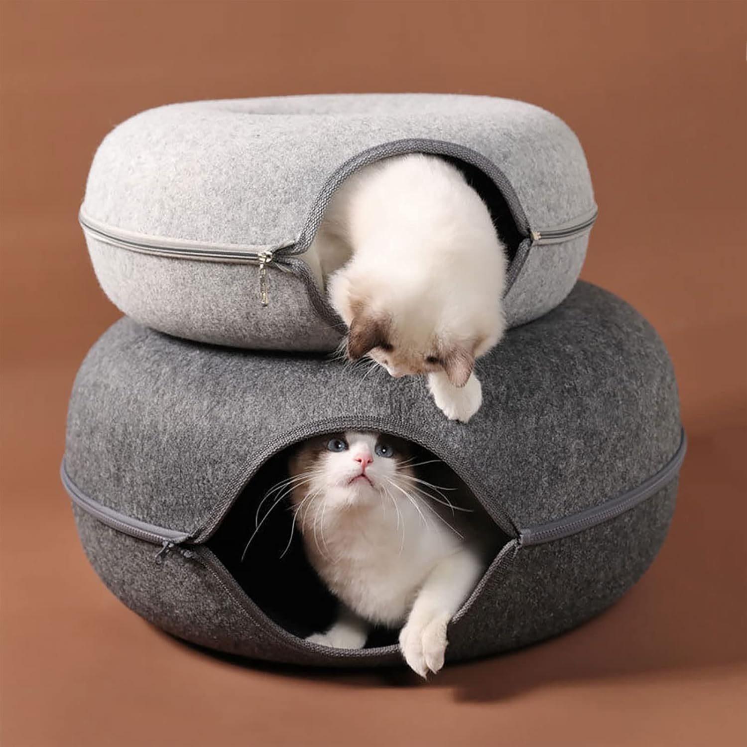 Two cats in cozy, stackable felt cat caves with zippers, one gray and one light gray, on a brown background. Perfect pet bed for comfort and style.