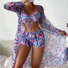 Woman modeling colorful abstract print beachwear set with matching cover-up, featuring vibrant pink and blue patterns, perfect for summer fashion.