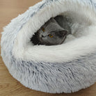 Gray cat nestled in a fluffy, round pet bed on wooden floor; cozy, soft, plush cat bed, perfect for comfort and warmth.