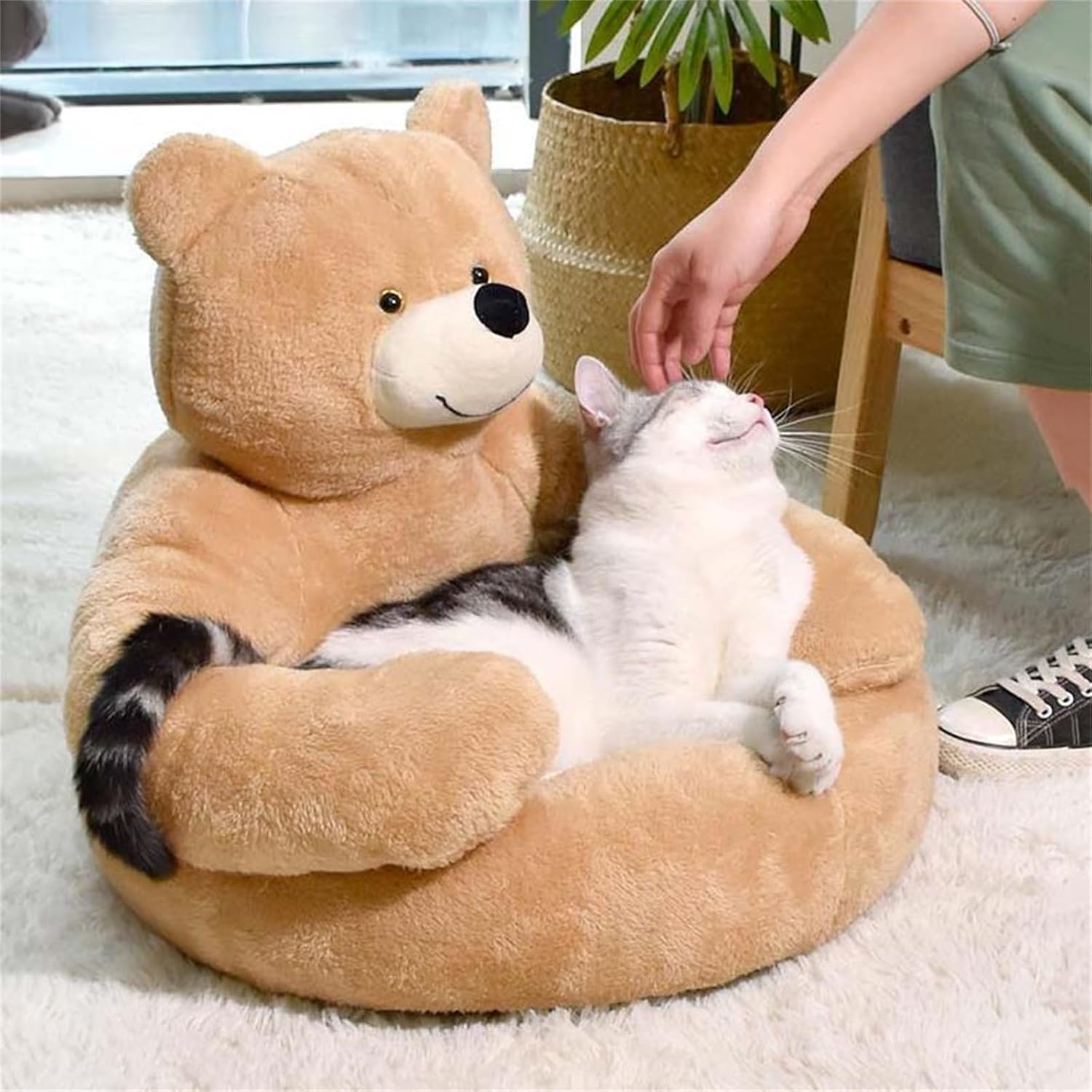 Cat lounging in a plush teddy bear-shaped pet bed, enjoying a gentle head scratch. Cozy pet furniture, perfect for cat comfort and relaxation.