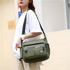 Woman carrying a stylish green crossbody bag with multiple zippered compartments, ideal for travel and daily use. Fashionable and functional accessory.