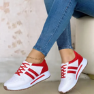 White and red athletic sneakers with perforated design, worn with blue jeans. Stylish casual footwear for women, perfect for walking or running.