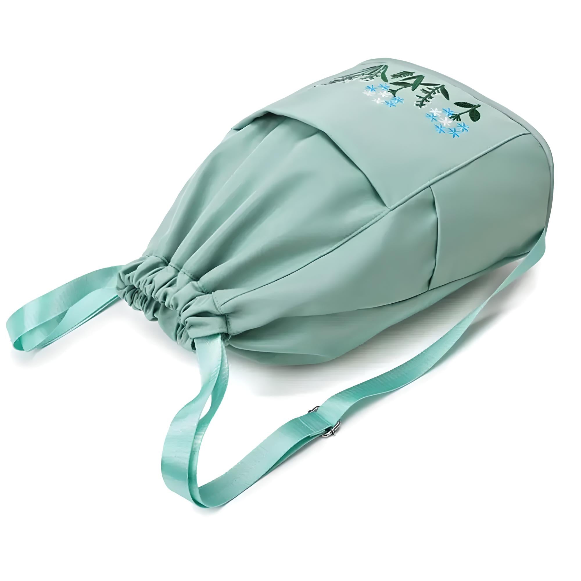 Mint green drawstring backpack with floral embroidery, adjustable strap, and spacious design. Perfect for travel, gym, or casual outings.