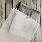 White mesh zipper pouch on wooden surface, containing transparent plastic bags. Ideal for organizing documents, travel essentials, or office supplies.