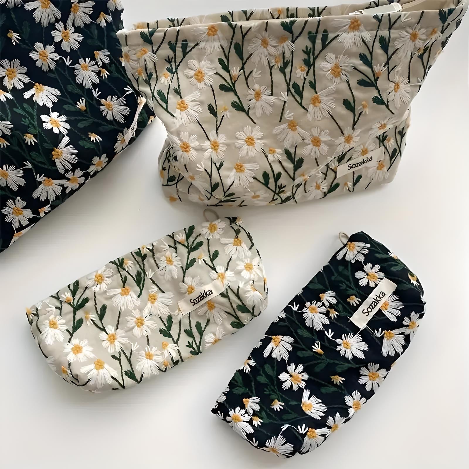 Floral print cosmetic bags set featuring daisy patterns on black and cream backgrounds. Stylish, eco-friendly travel pouches for makeup and toiletries.