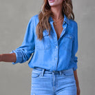 Woman wearing a stylish blue denim shirt with rolled-up sleeves and matching jeans, showcasing casual fashion trends.